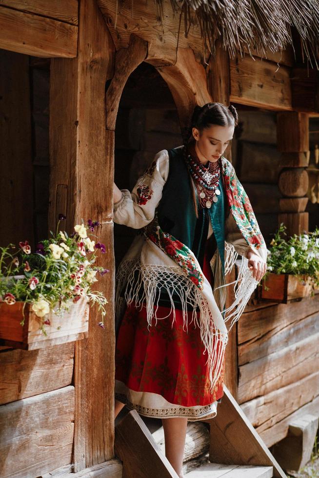 ung flicka går ut ur huset i en traditionell ukrainsk klänning foto