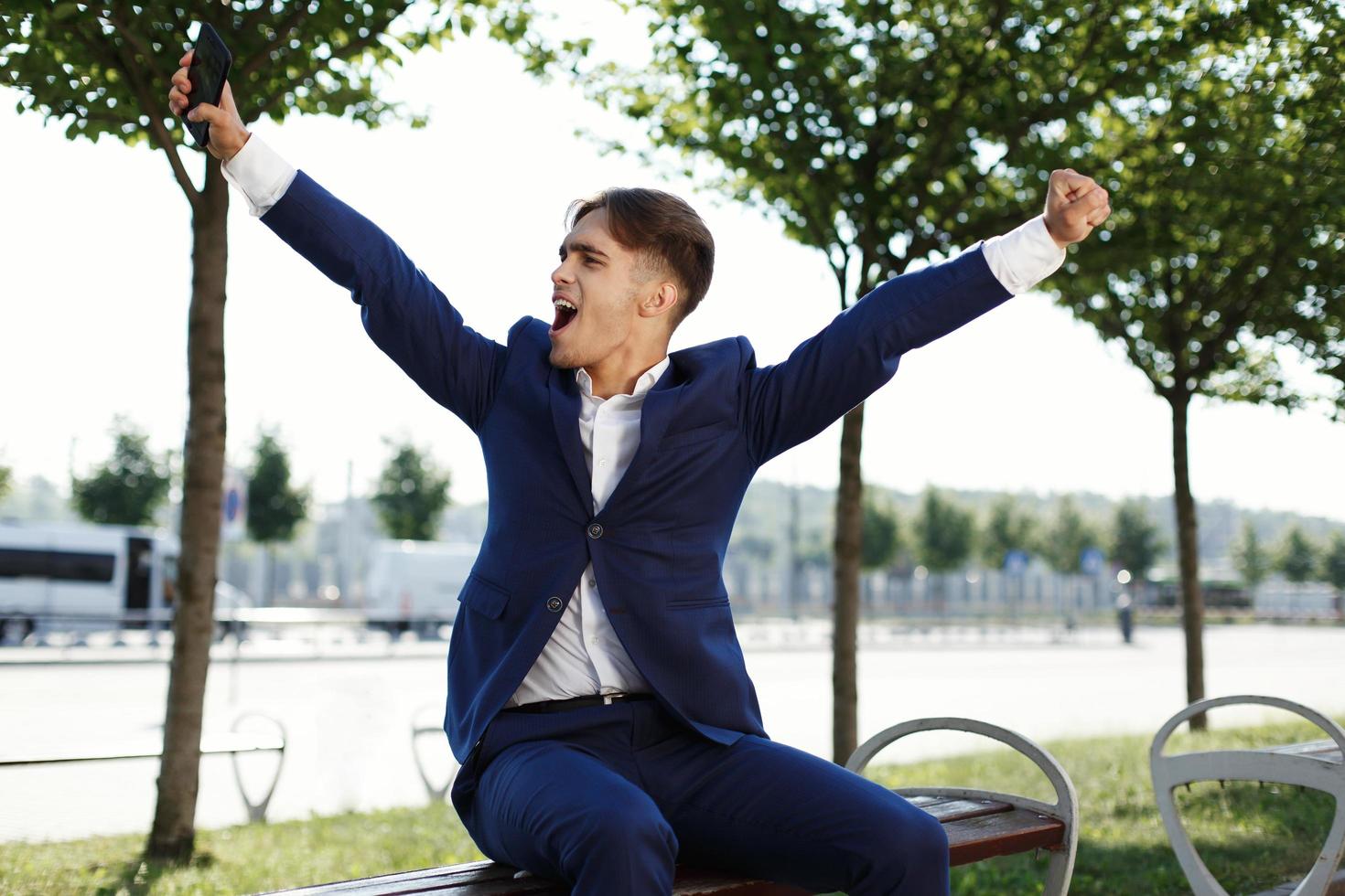 glad kille som sitter på en bänk i parken foto