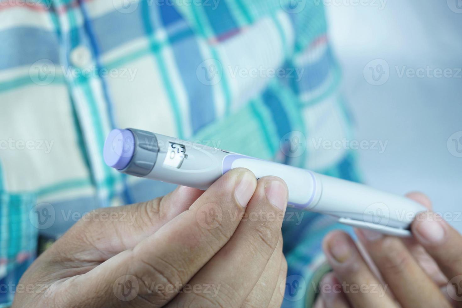 delvis suddig bild av man innehav insulin penna. medicinsk Utrustning är lätt till själv injektion foto