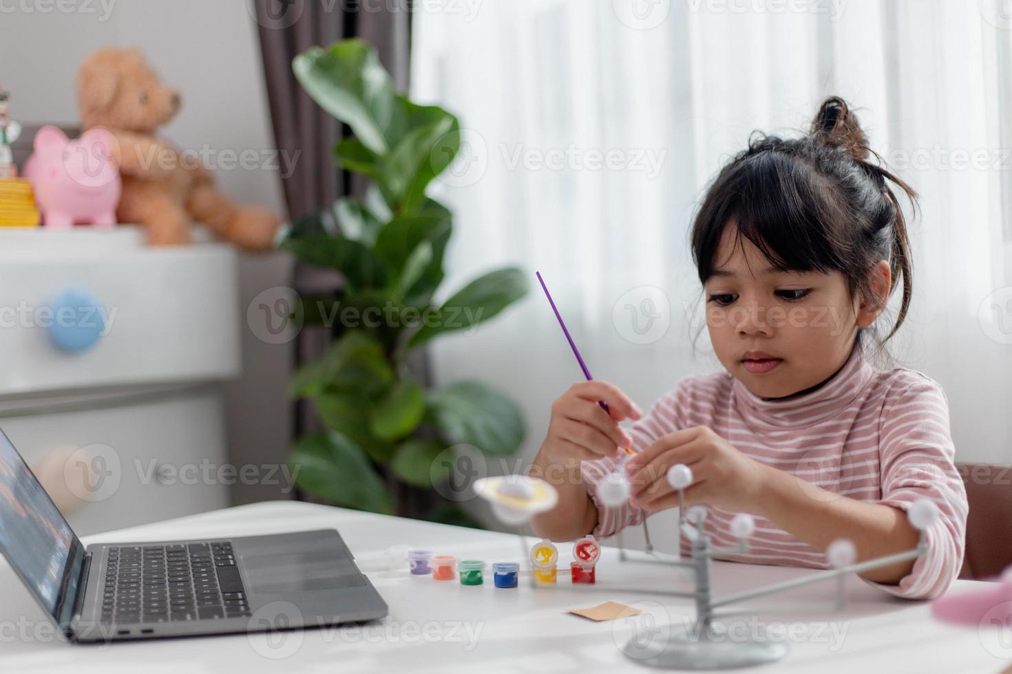 asiatisk liten flicka studier de sol- systemet i geografi klass. ser på de skala modell av planeter foto