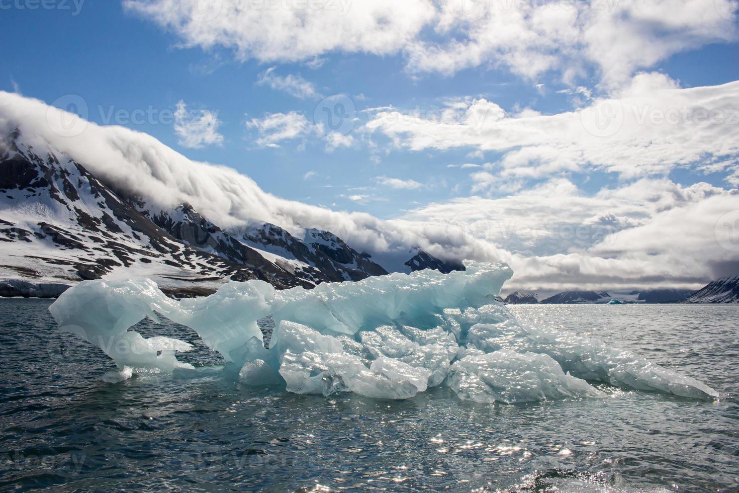ett isberg flytande i främre av bergen i svalbard foto