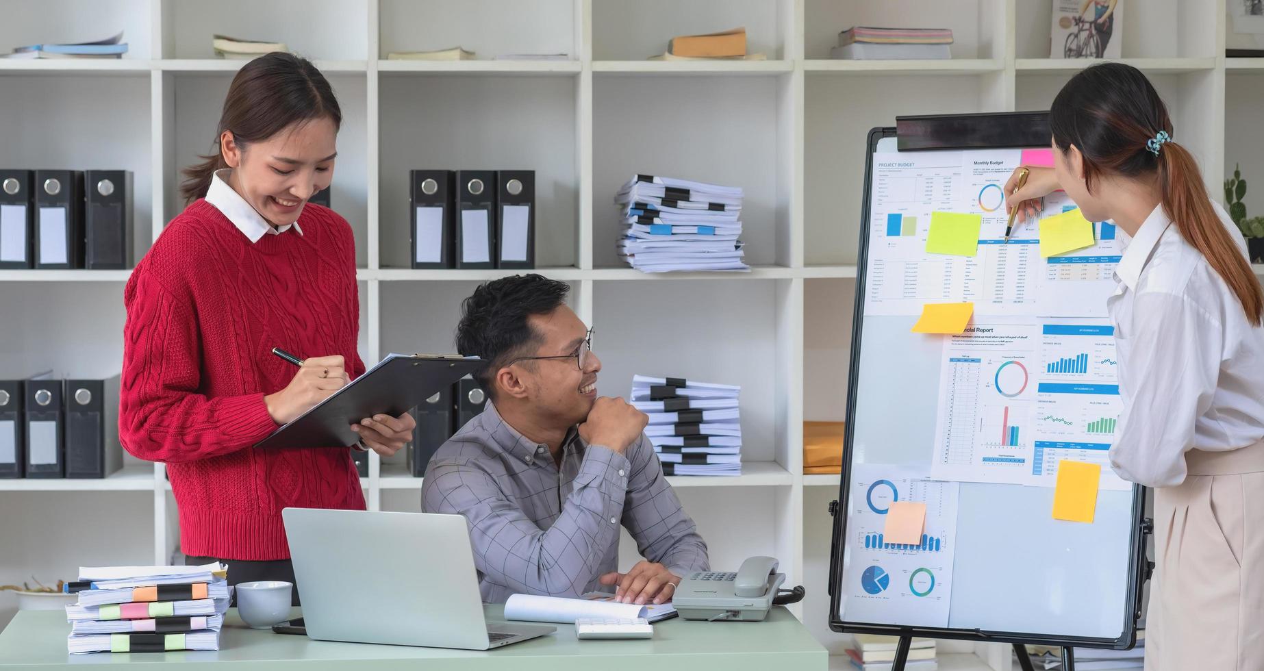 ett team av affärsmän planerar med sina bärbara datorer och diagram för sina vinster och använder en kalkylator för att beräkna företagets årliga saldo. foto
