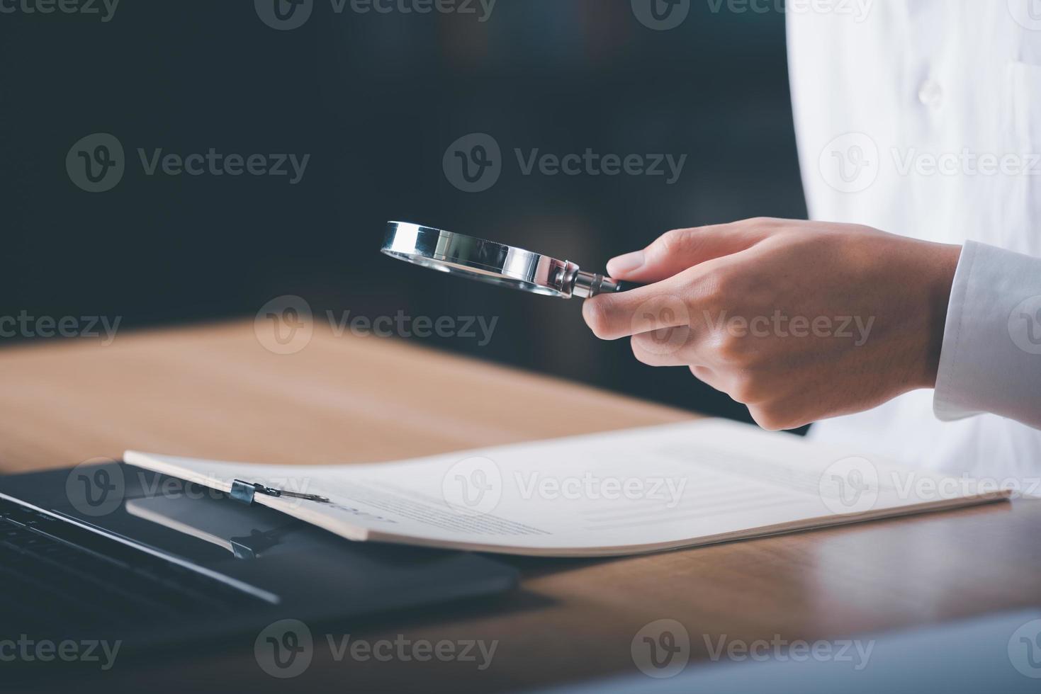 affärsman som visar undersökning av företag dokument med en förstorande glas, revision och bedrägeri utredning, tjänsteman finansiell undersökning för företag ,de procedur för granskning dokument foto