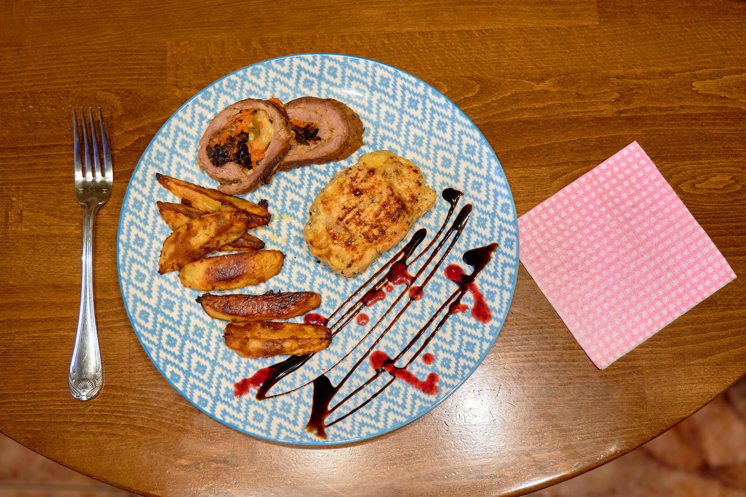 en vackert presenteras maträtt av friterad kött och bakad potatisar i en tallrik den där sitter på de dining tabell. foto