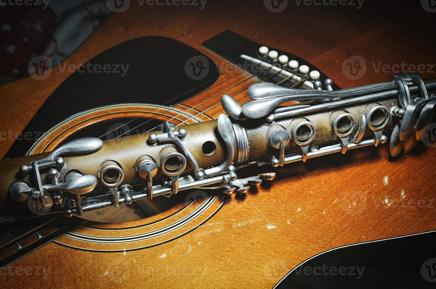 ett antik klarinett vilar på akustisk gitarr foto