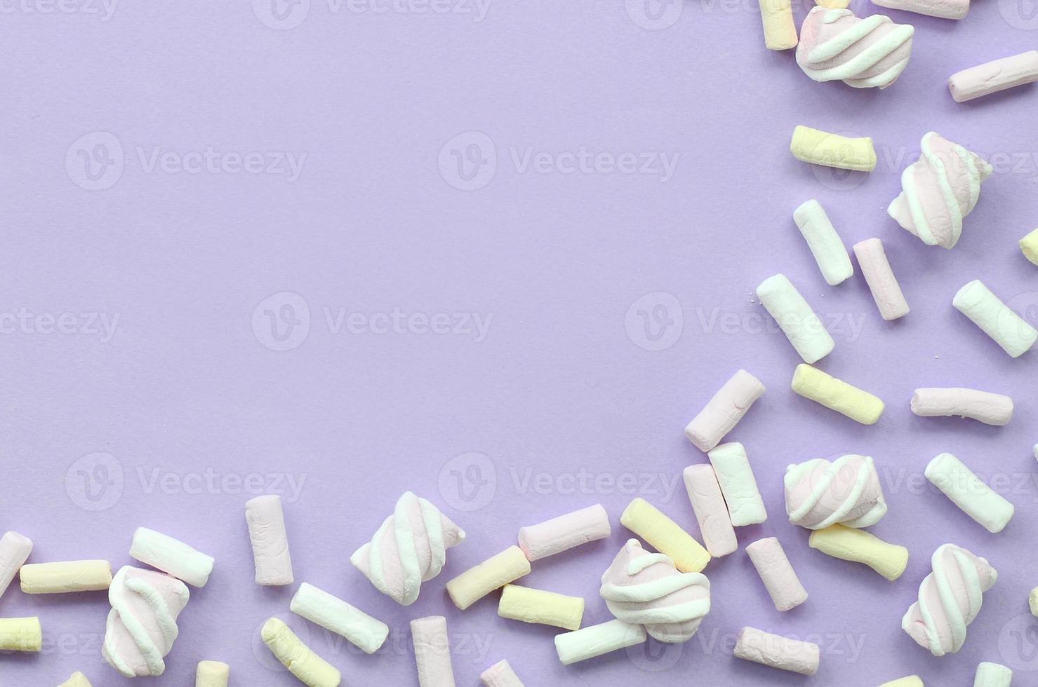 färgrik marshmallow lagd ut på violett papper bakgrund. pastell kreativ texturerad ramverk. minimal foto
