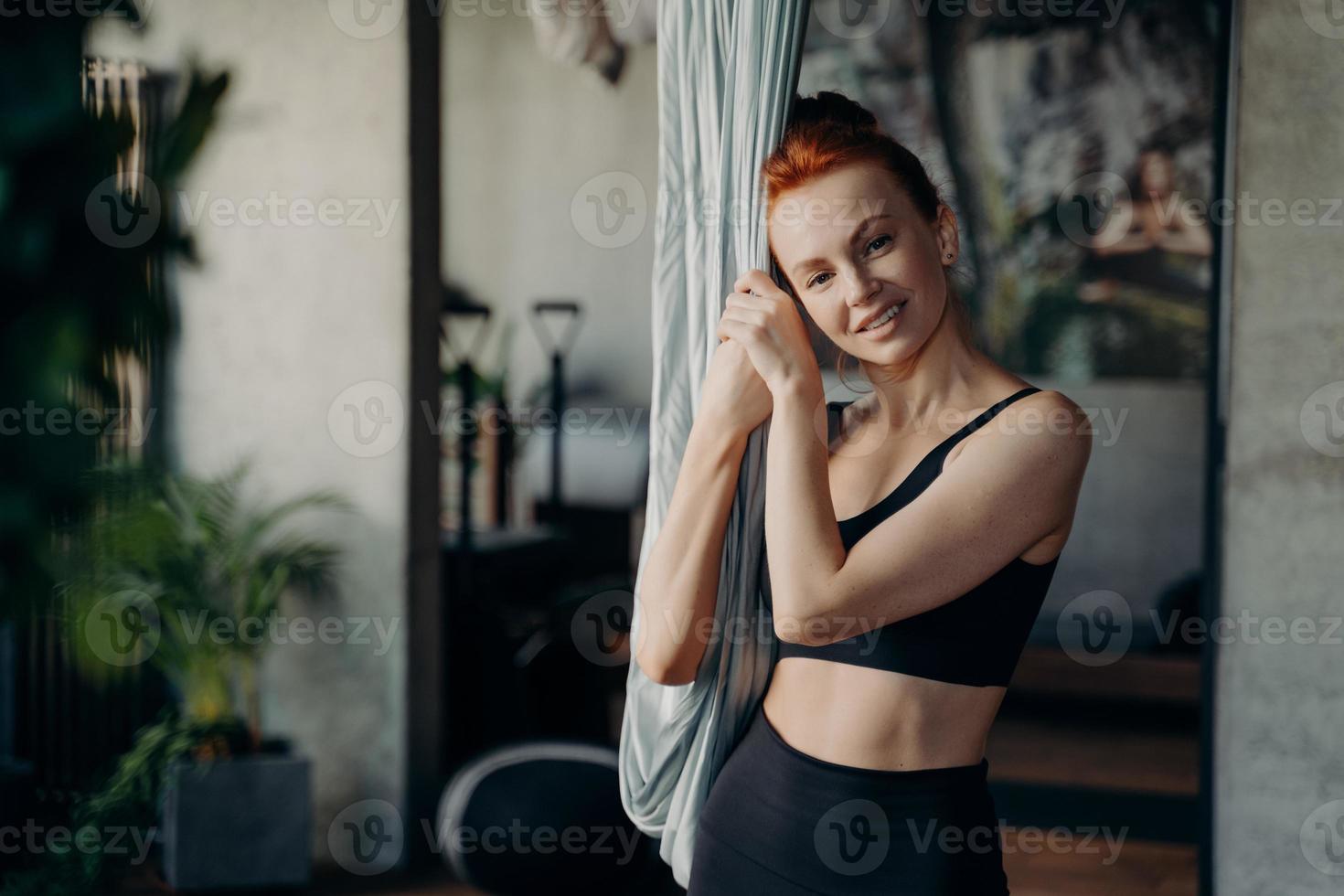 trevlig ser röd håriga kondition kvinna i svart sportkläder vilar efter antenn yoga klass foto