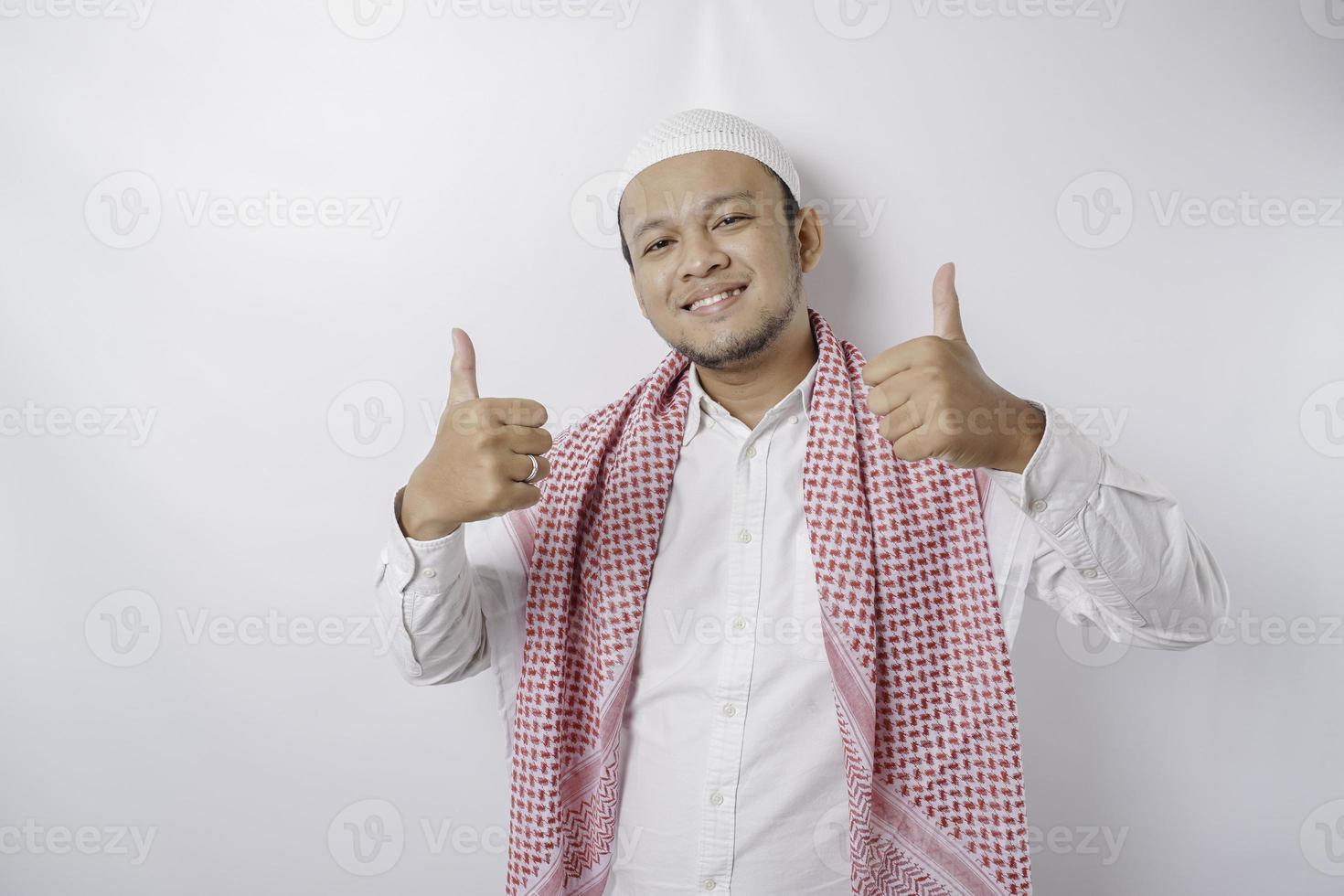 upphetsad asiatisk muslim man ger tummen upp hand gest av godkännande, isolerat förbi vit bakgrund foto