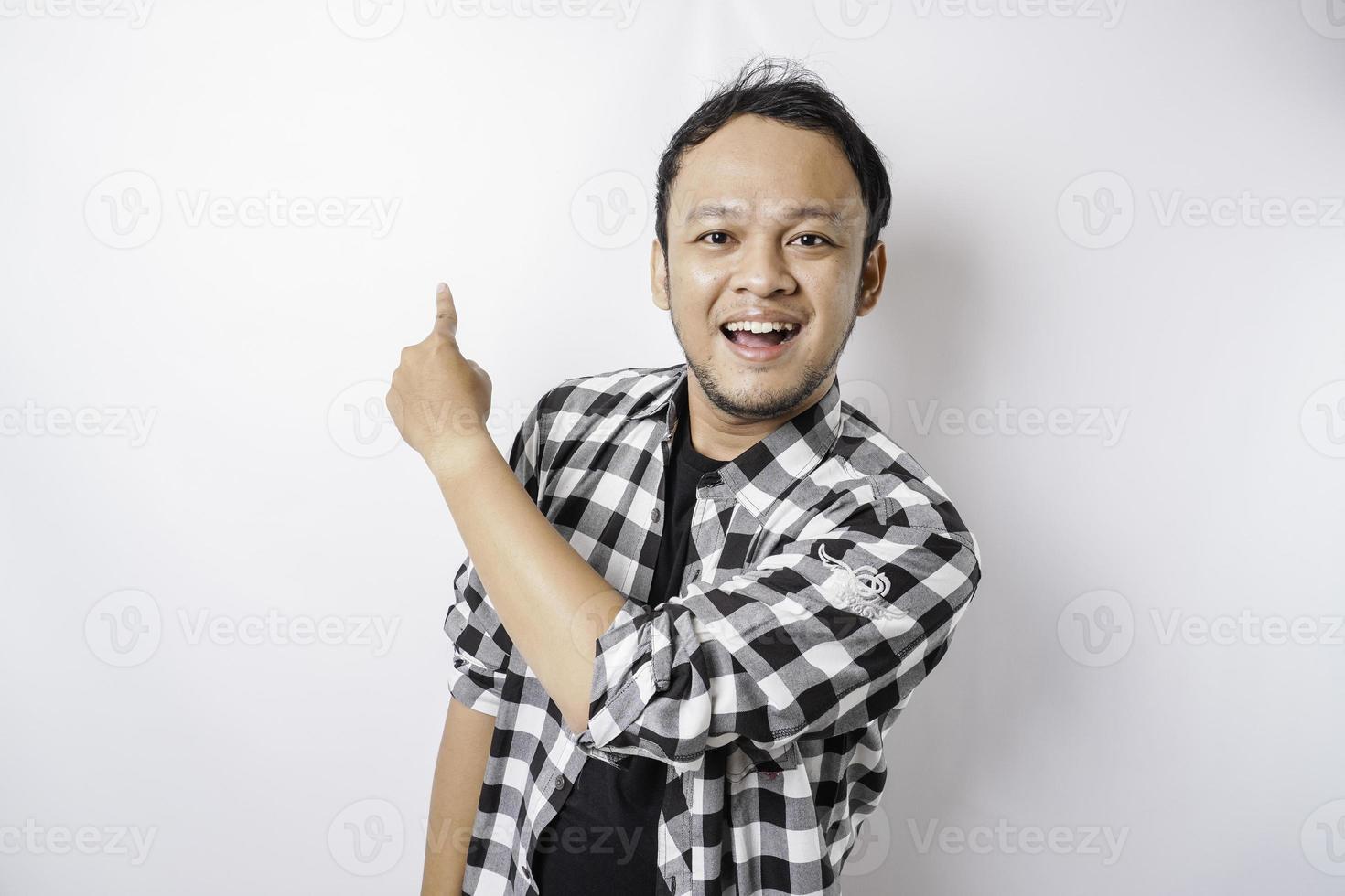 leende asiatisk man bär tartan skjorta är pekande på de kopia Plats på topp av honom, isolerat förbi vit bakgrund foto