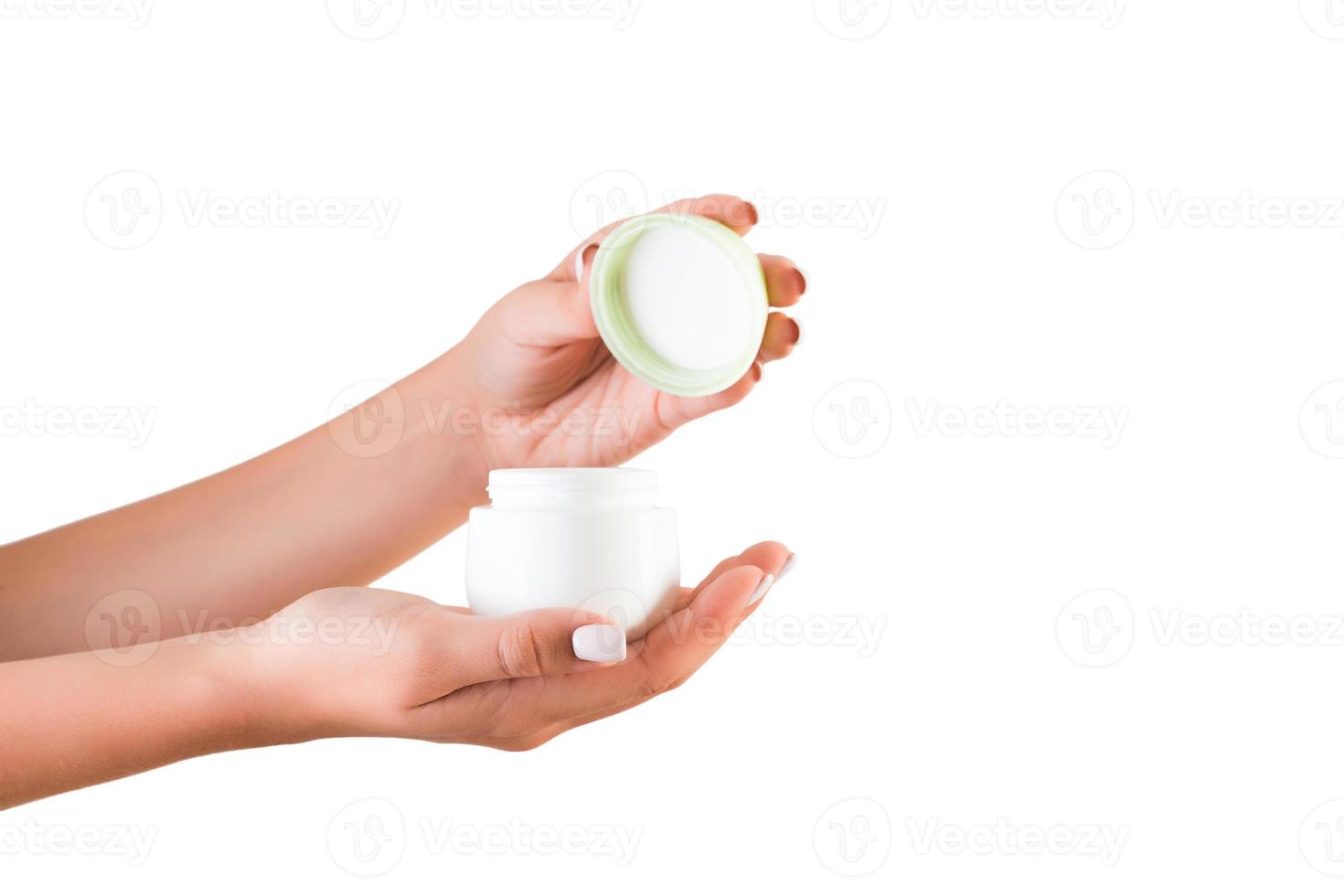 kvinna hand innehav grädde flaska av lotion isolerat. flicka öppning burk kosmetisk Produkter på vit bakgrund foto