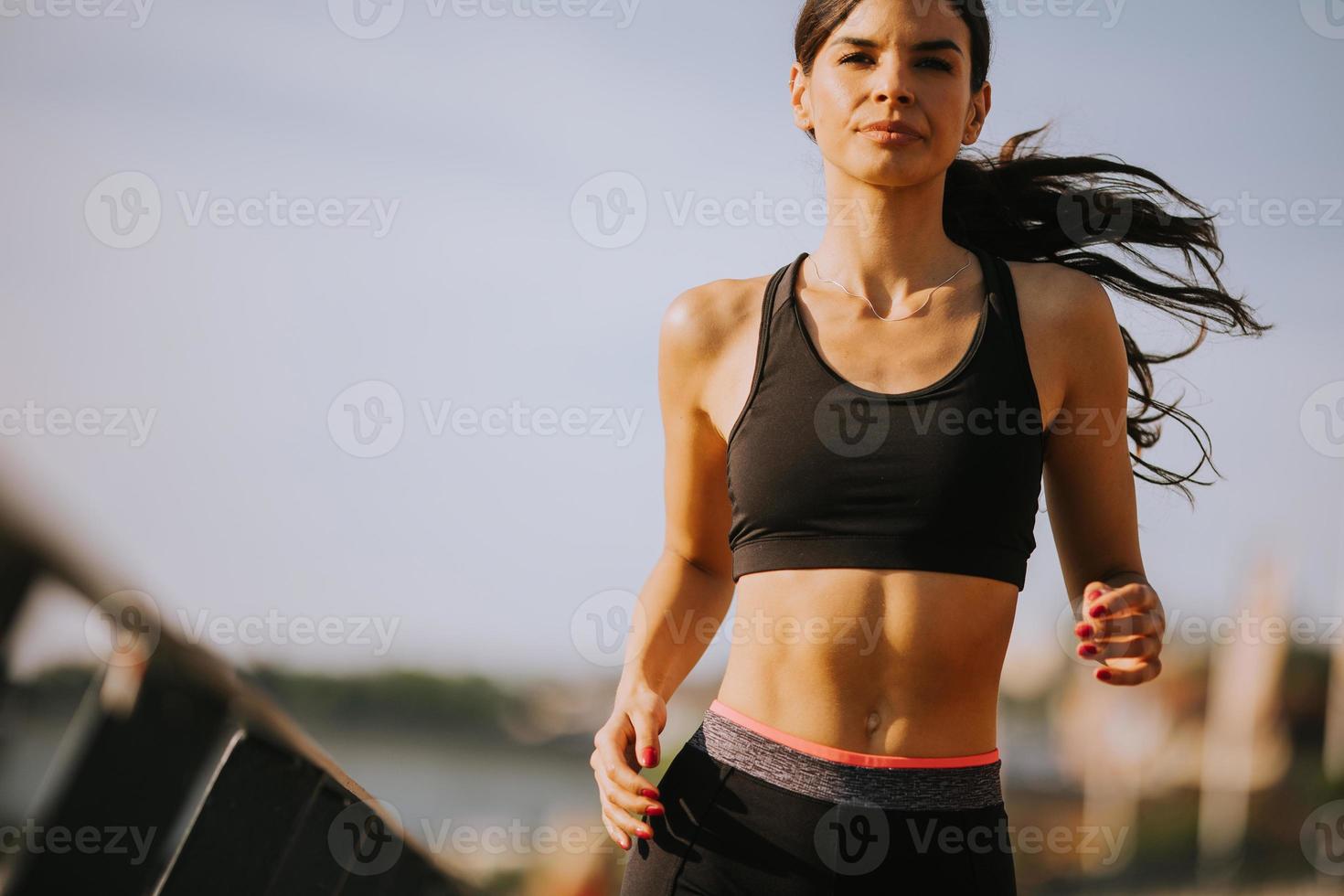 aktiva ung skön kvinna löpning på de promenad längs de flodstrand foto