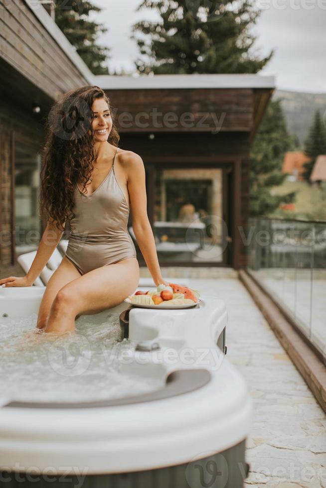 ung kvinna njuter i utomhus- varm badkar på semester foto