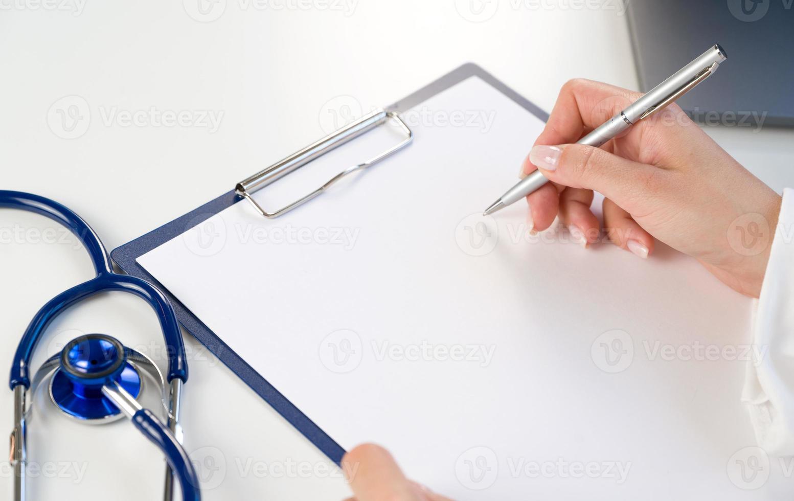 medicinsk mall för text. närbild av läkare händer innehav penna på papper läsplatta med stetoskop nära foto