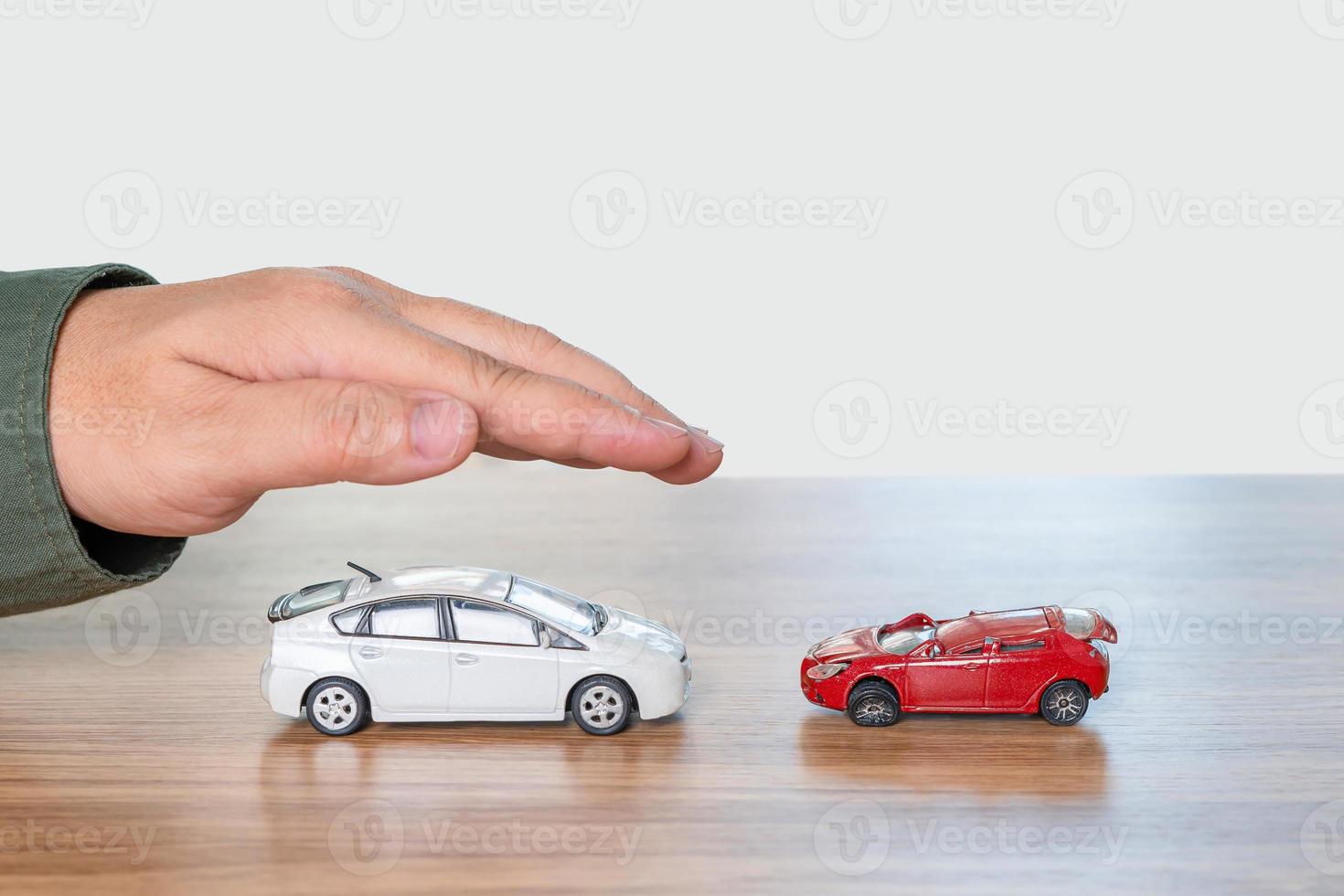 jämförelser av de olycka begrepp i använda sig av bil , leksak bil perfekt tillstånd i med hand en man skydd och jämföra de skadad leksak bilar på tabell och vit bakgrund foto