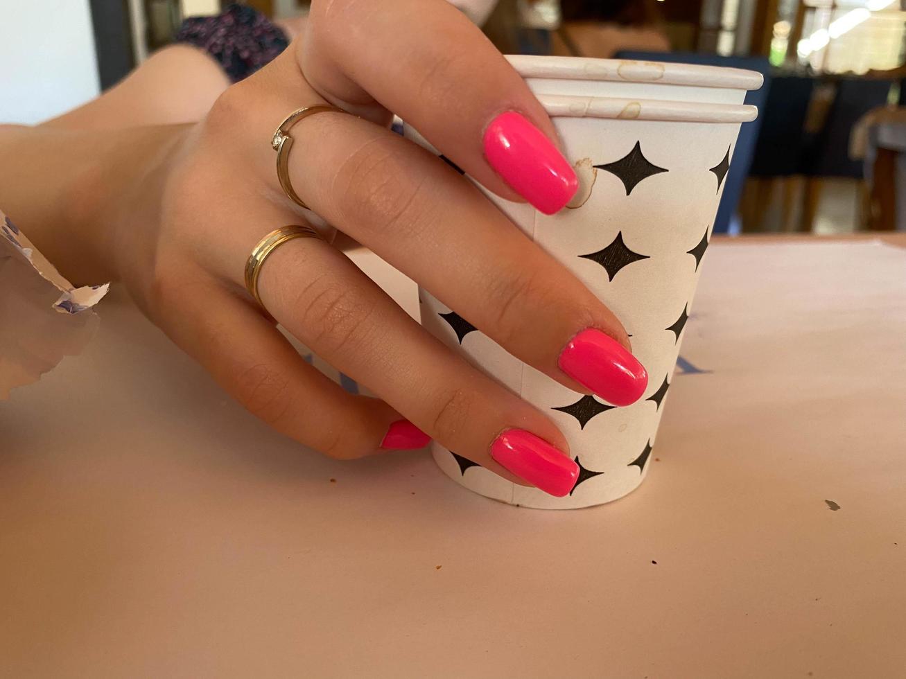 kopp av kaffe i kvinnas händer med ljus röd manikyr foto