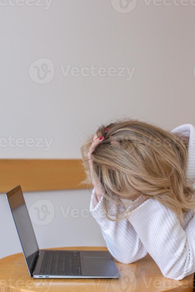 skön flicka frilansare känsla trött och betonade medan använder sig av en bärbar dator och arbetssätt avlägset från Hem. företag kvinna på de kontor är deprimerad. foto