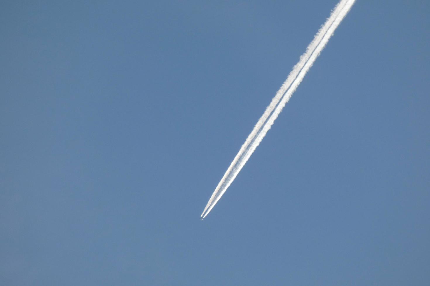 vit vakna av ett flygplan under de blå himmel foto