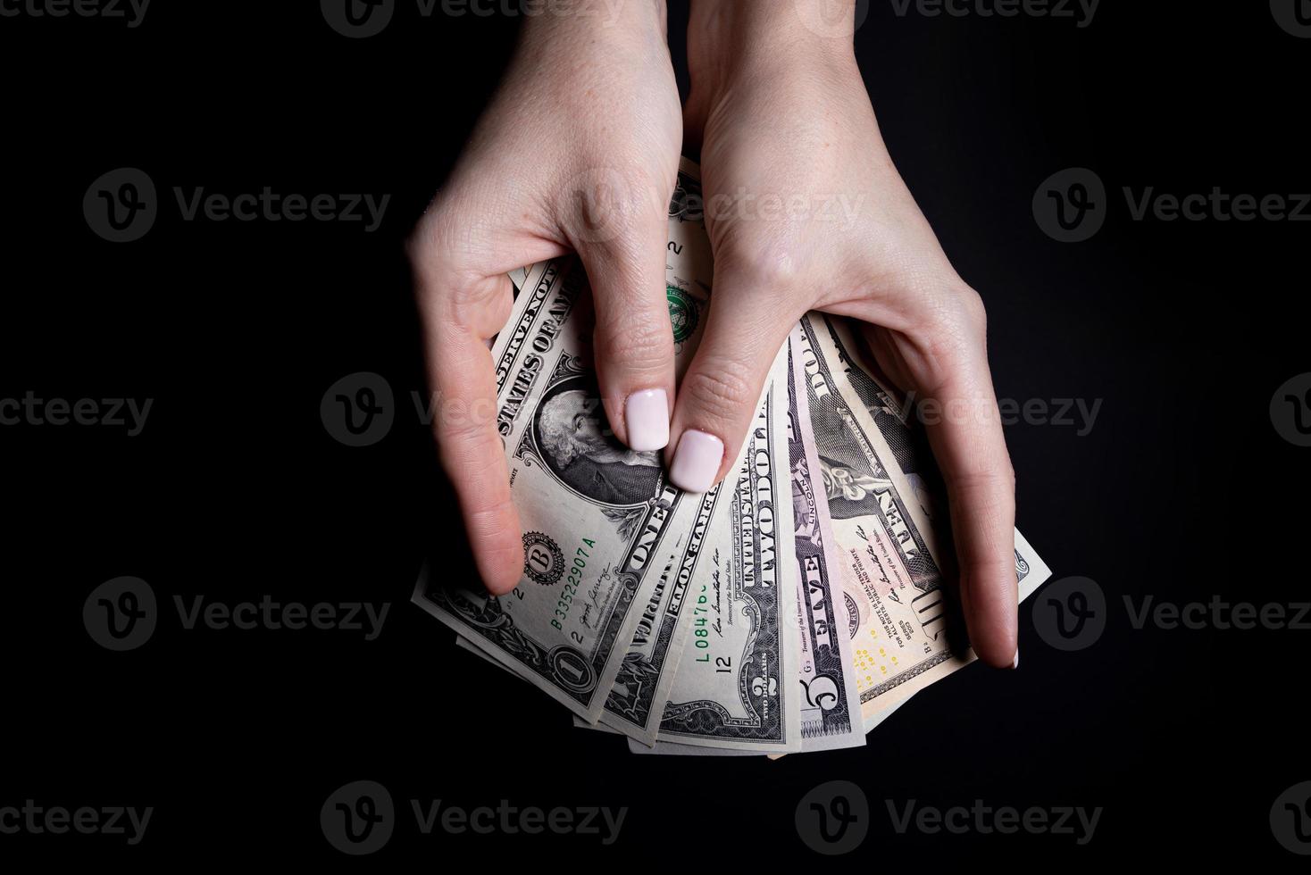 två händer med dollar. närbild kvinna hand ger pengar för något med isolerat på svart bakgrund, räkna, betalande, handla med dollar, korruption, räkning dollar sedlar på svart foto