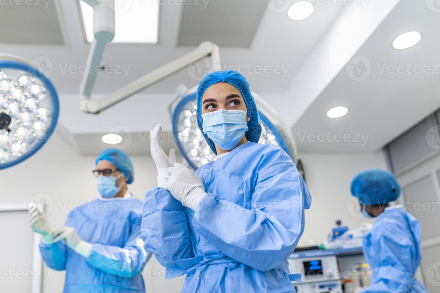 porträtt av kvinna kirurg i kirurgisk enhetlig i drift teater ser bort. läkare i scrubs och medicinsk mask i modern sjukhus rörelse rum. foto