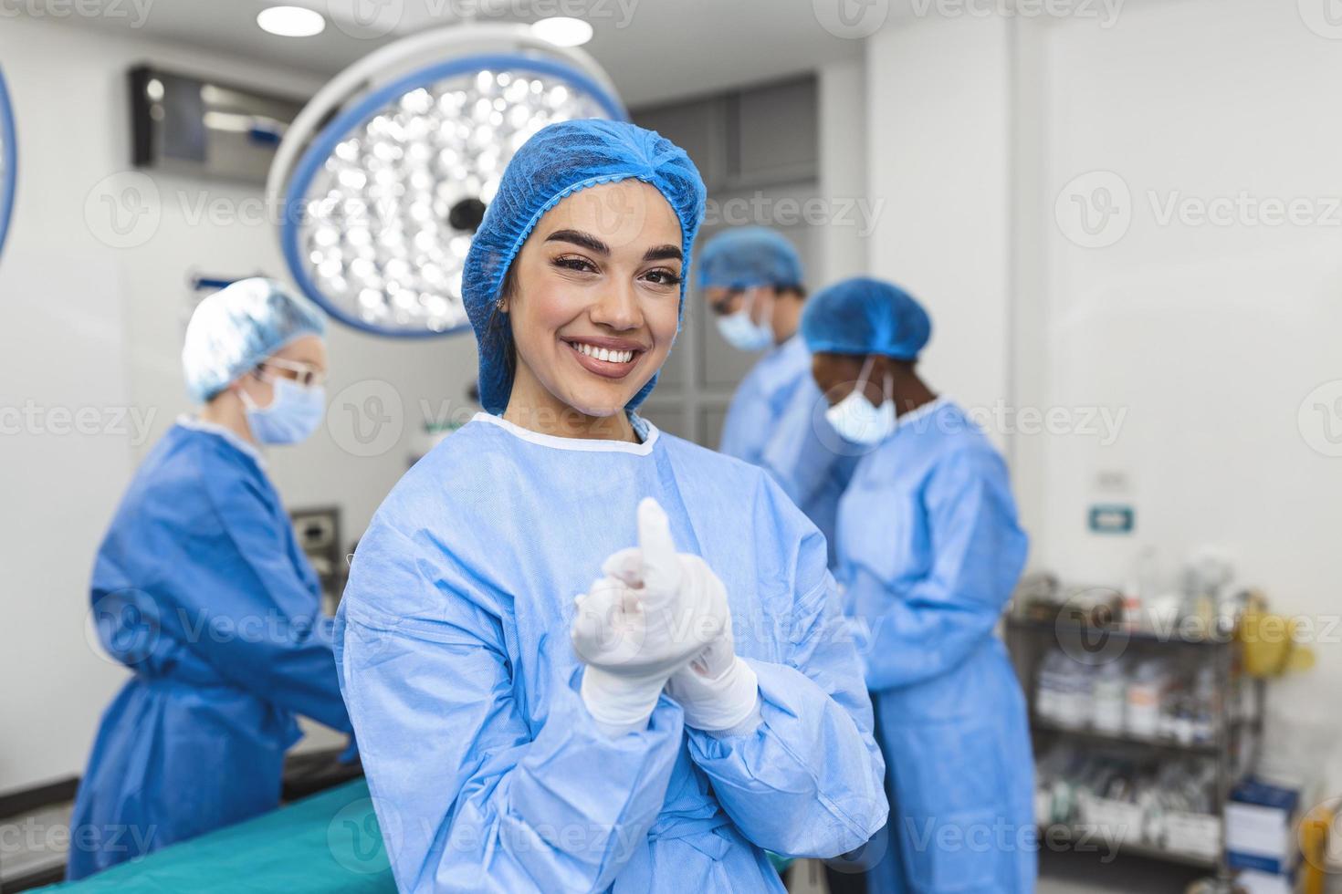 porträtt av skön kvinna läkare kirurg sätta på medicinsk handskar stående i drift rum. kirurg på modern rörelse rum foto