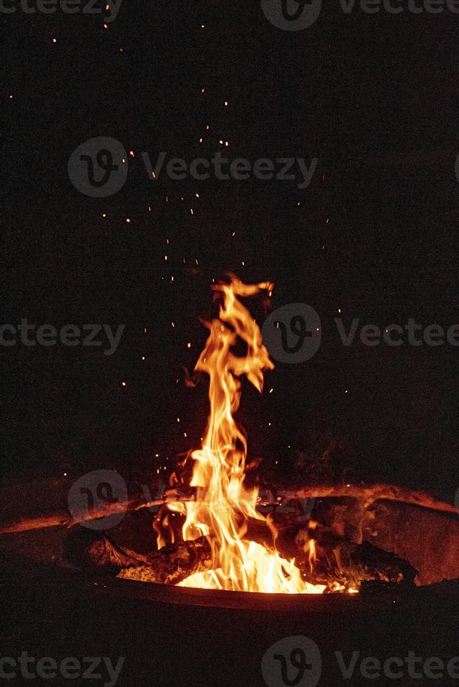 camping runt om en lägereld på natt tittar på de gnistor flyga in i de luft foto