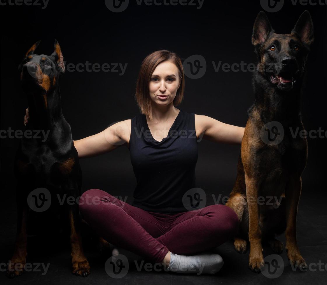 porträtt av en doberman hund och en belgisk herde hund med en flicka ägare. foto