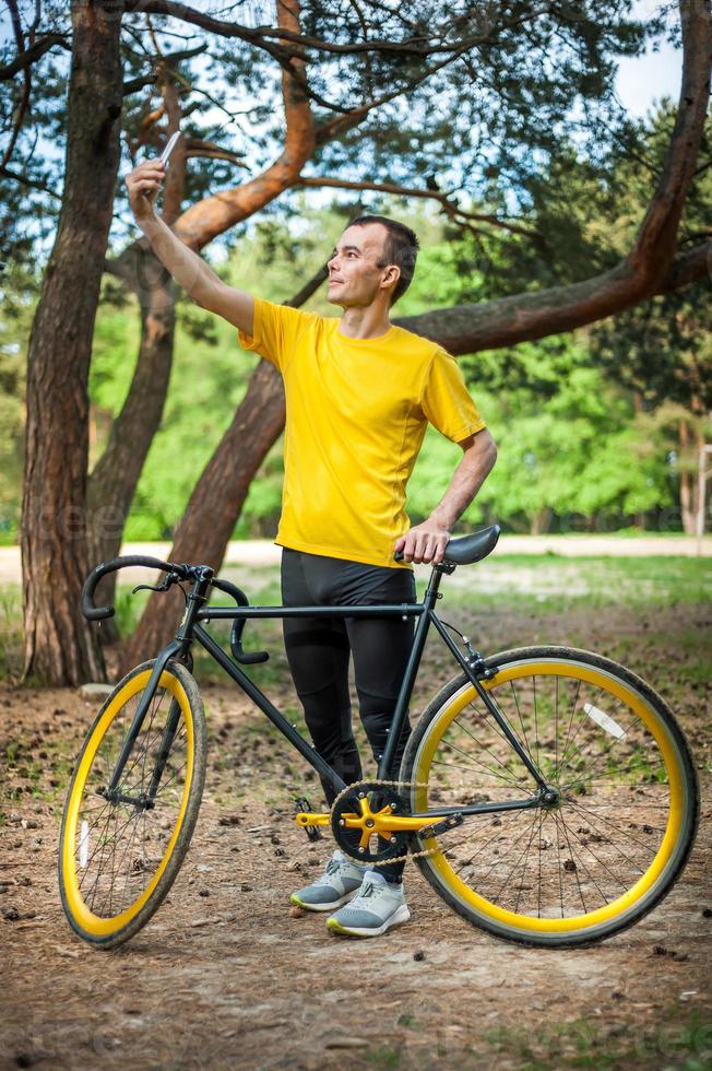 en ung man som tar en selfie med sin cykel. foto