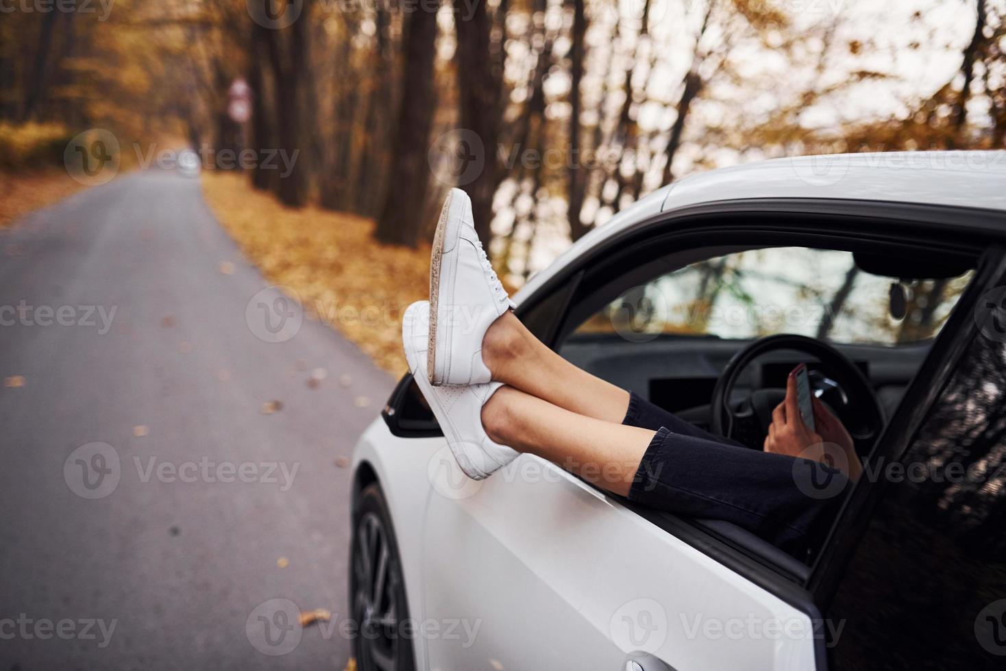 kvinnas ben är av de bil fönster. modern varumärke ny bil i de skog foto