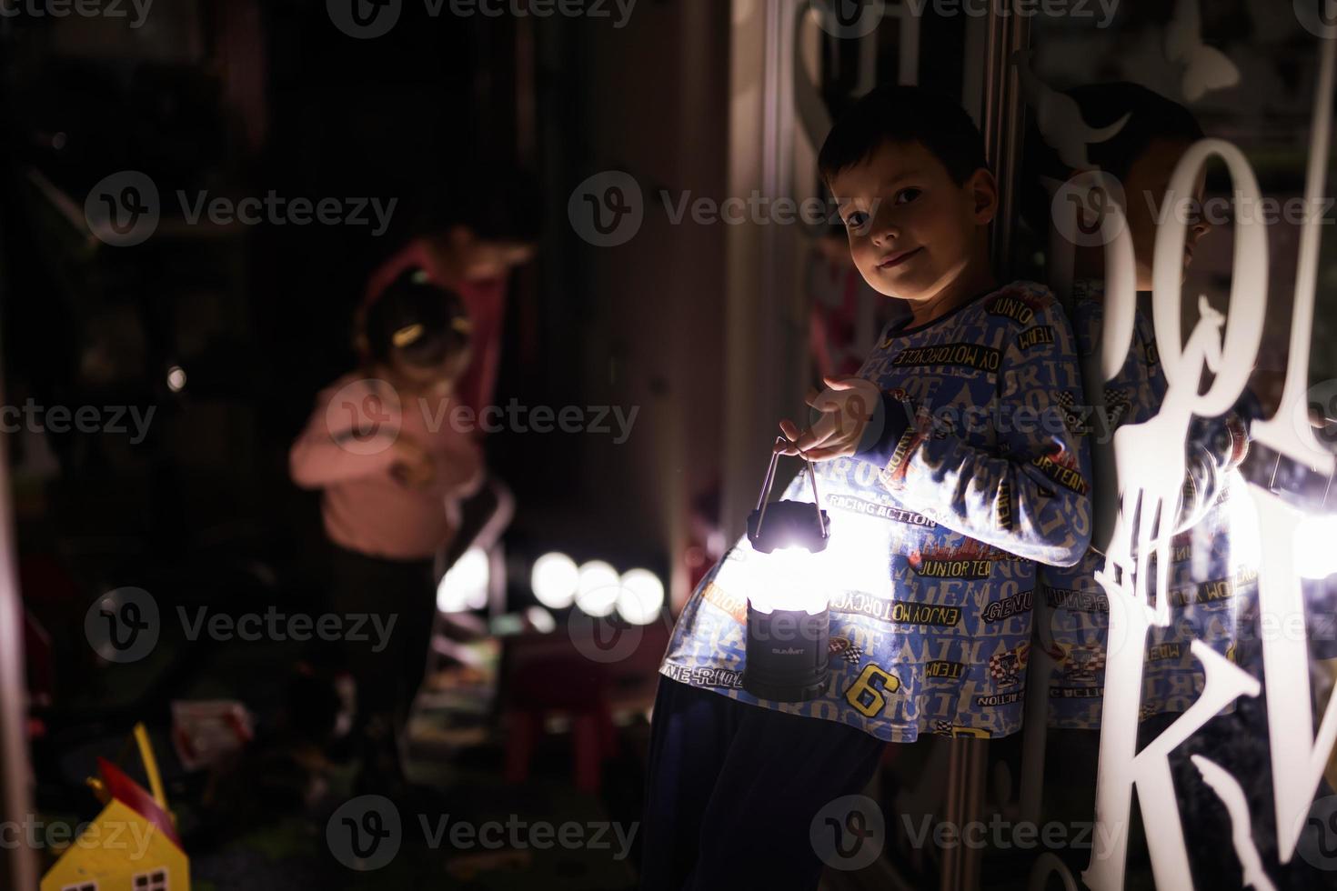 pojke på Hem under en mörkläggning använder sig av ficklampa lykta. foto