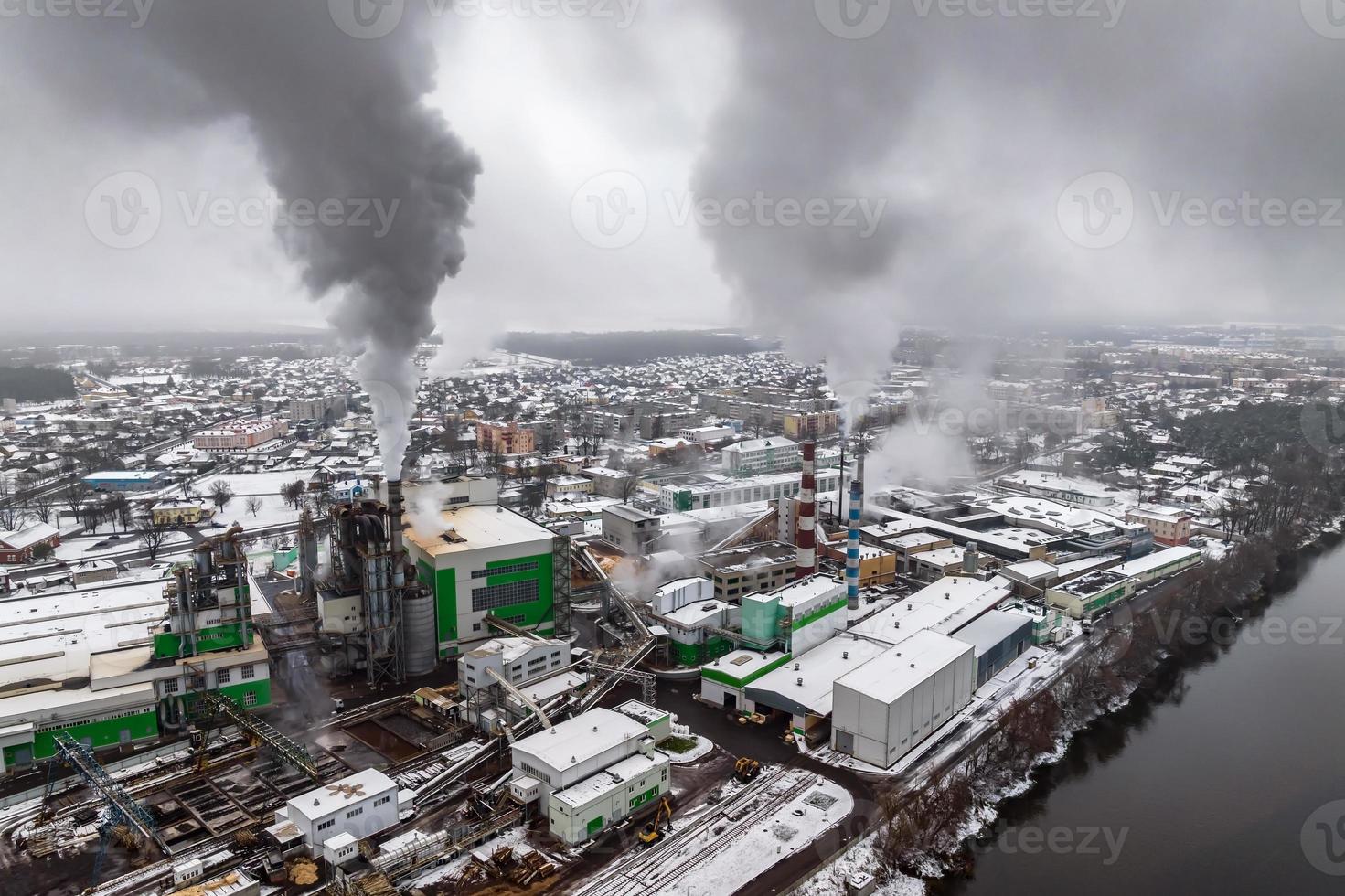 vinter- panorama- antenn se av de rök av rör av en kemisk växt eller träbearbetning företag. luft och vatten förorening begrepp. foto