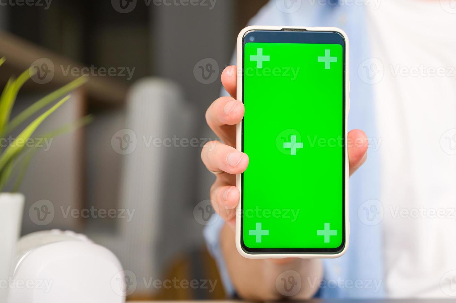 attrapp bild av en man innehav och visar smartphone med grön krom skärm foto