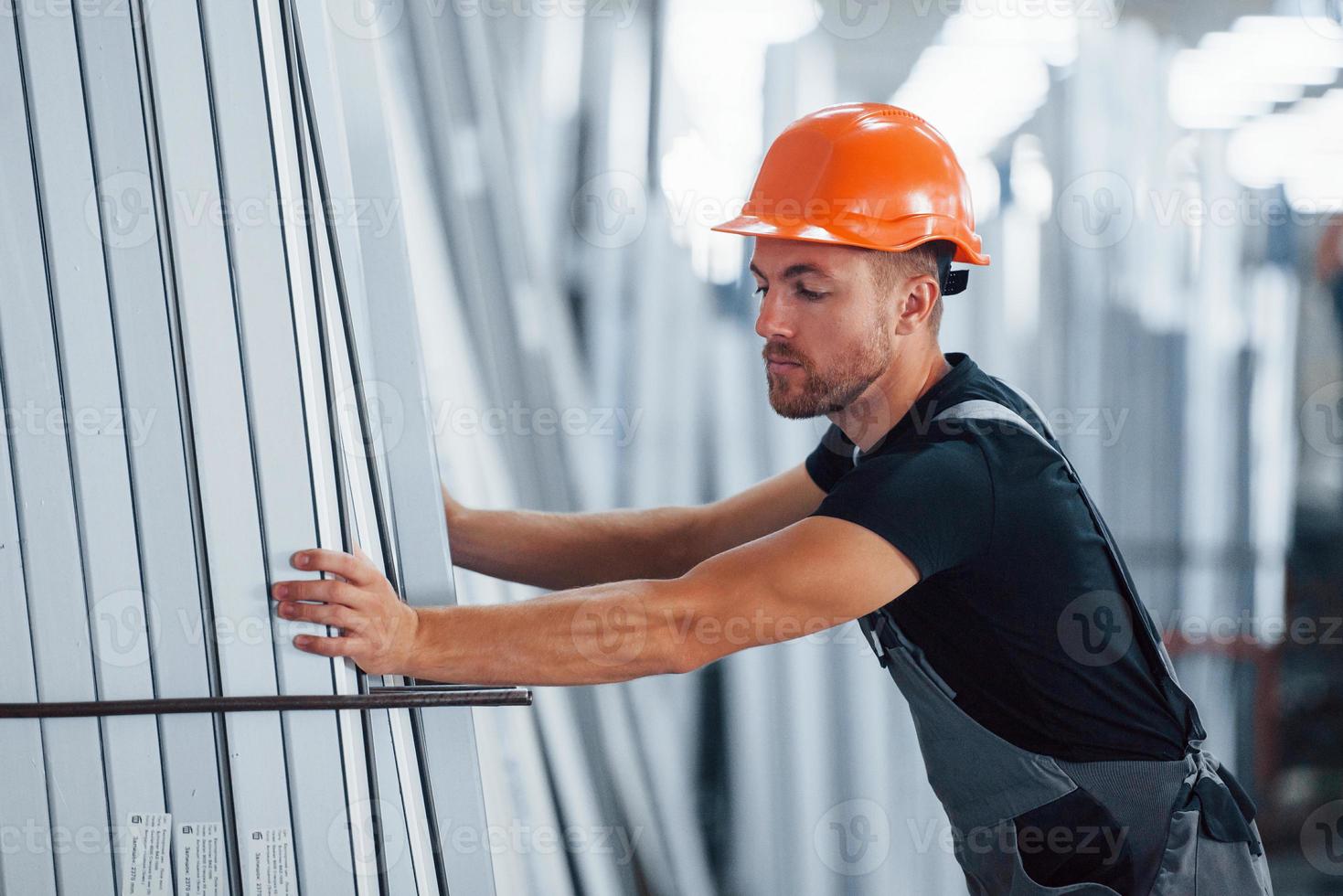 i de lagring med många av objekt. industriell arbetstagare inomhus i fabrik. ung tekniker med orange hård hatt foto