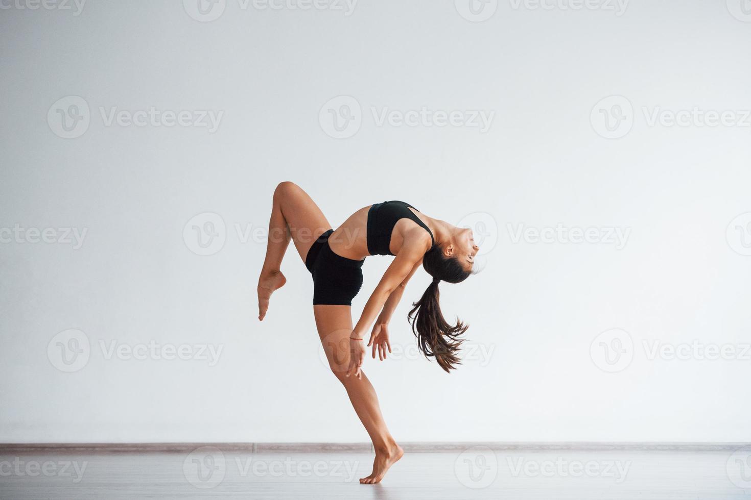 full längd Foto. ung sportig kvinna i svart kläder med smal kropp typ i de friska Centrum håller på med övningar foto