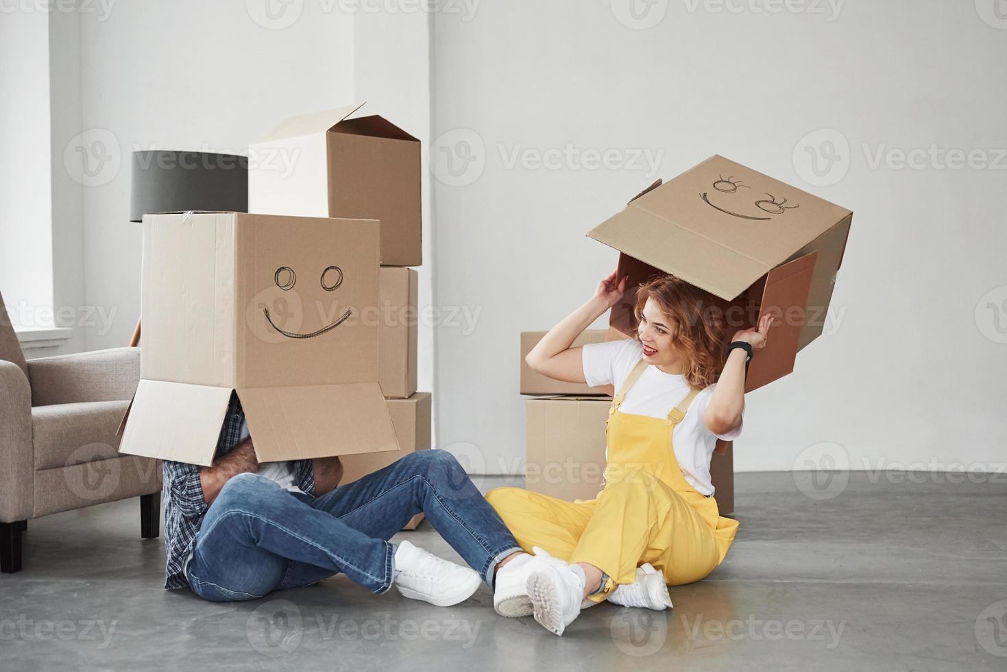 bär lådor på huvudena. lyckligt par tillsammans i sitt nya hus. föreställning om att flytta foto