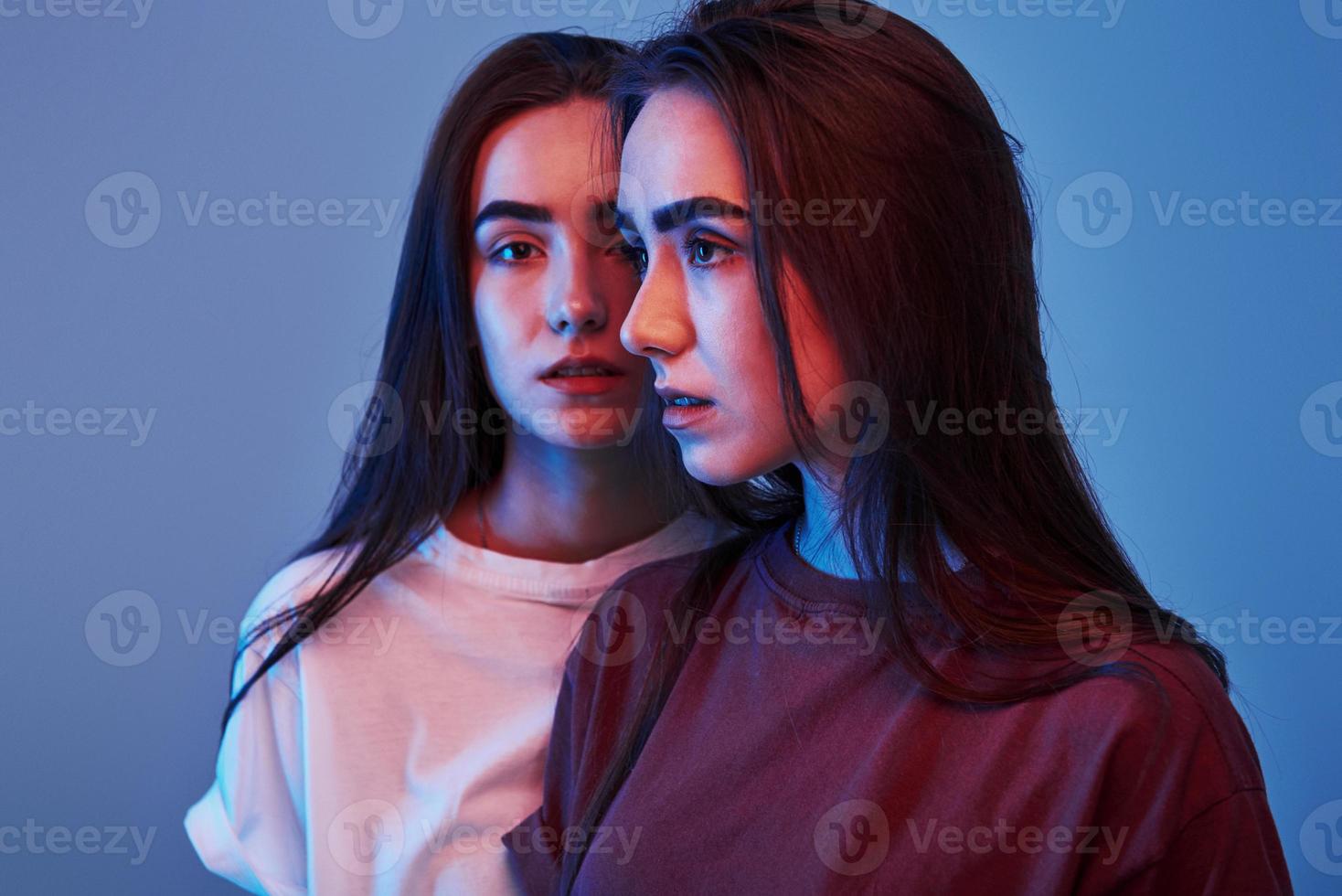 Foto av två skön tvillingar. studio skott inomhus med neon ljus
