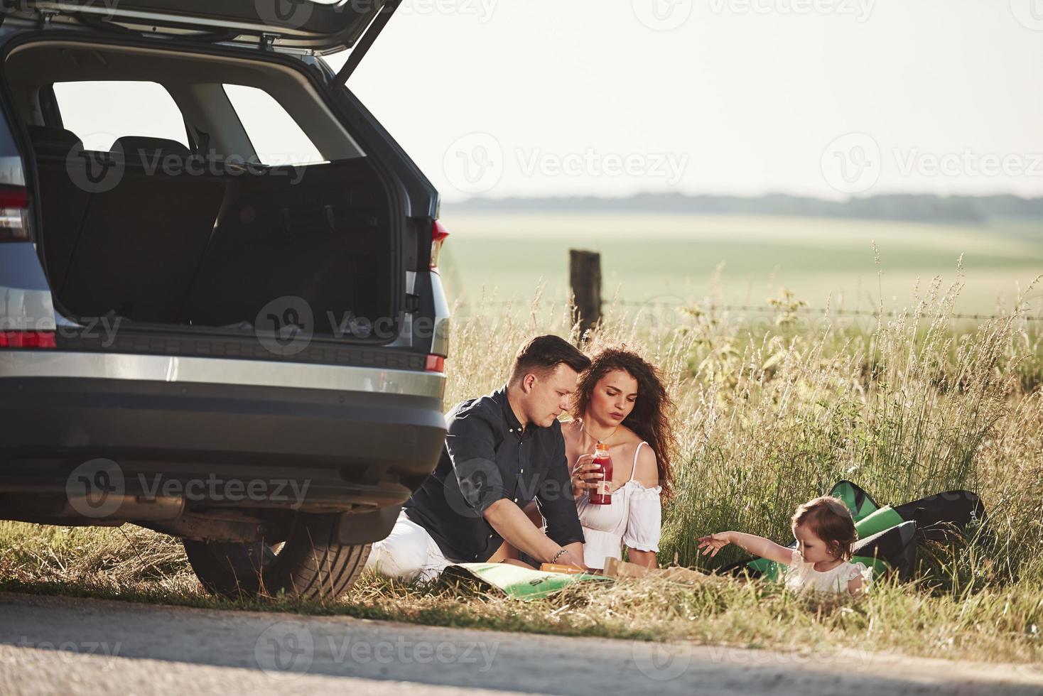 lugna humör. familj ha picknick på landsbygden nära silver- bil på solnedgång foto