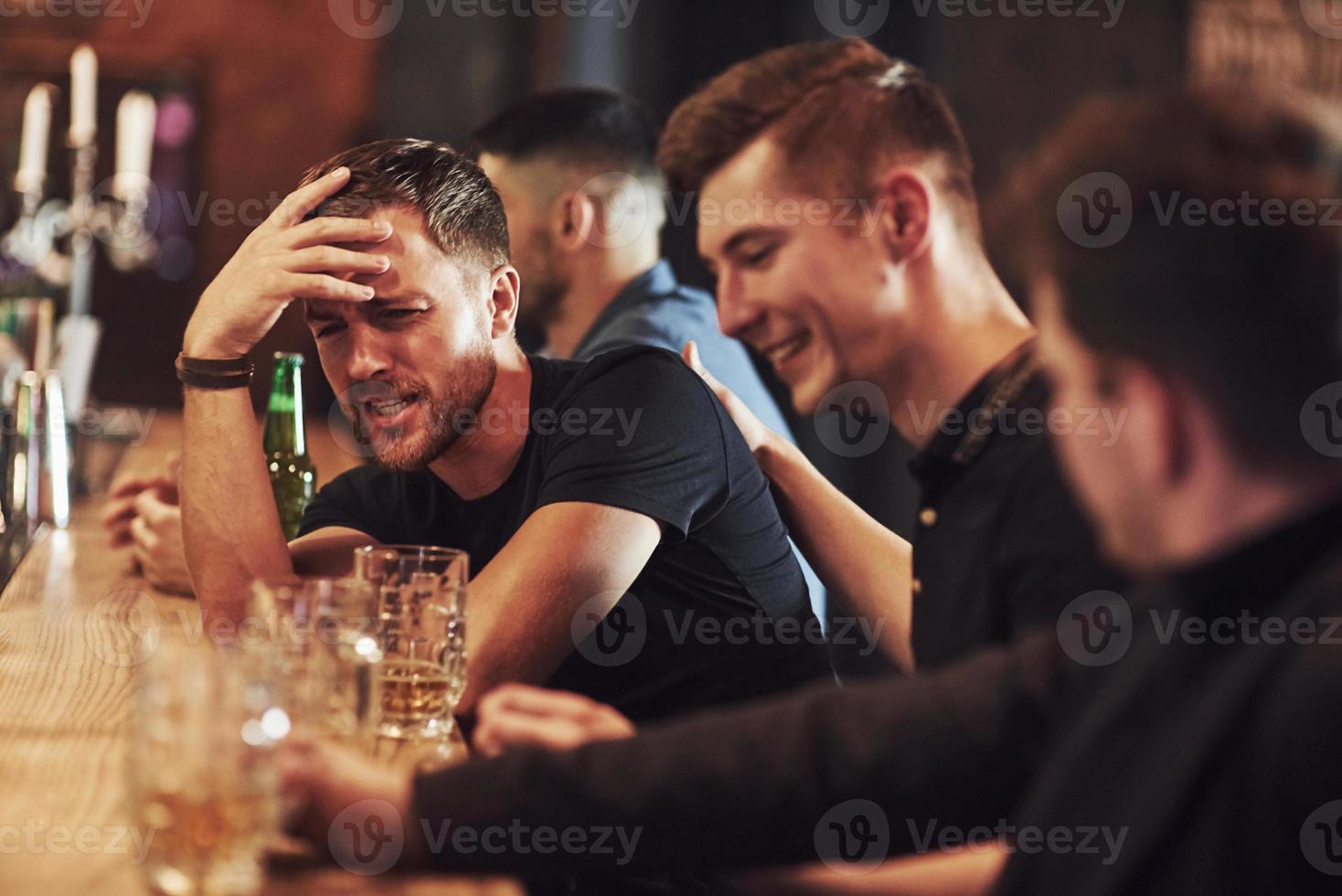 sida se. vänner vilar i de pub med öl i händer. har konversation foto