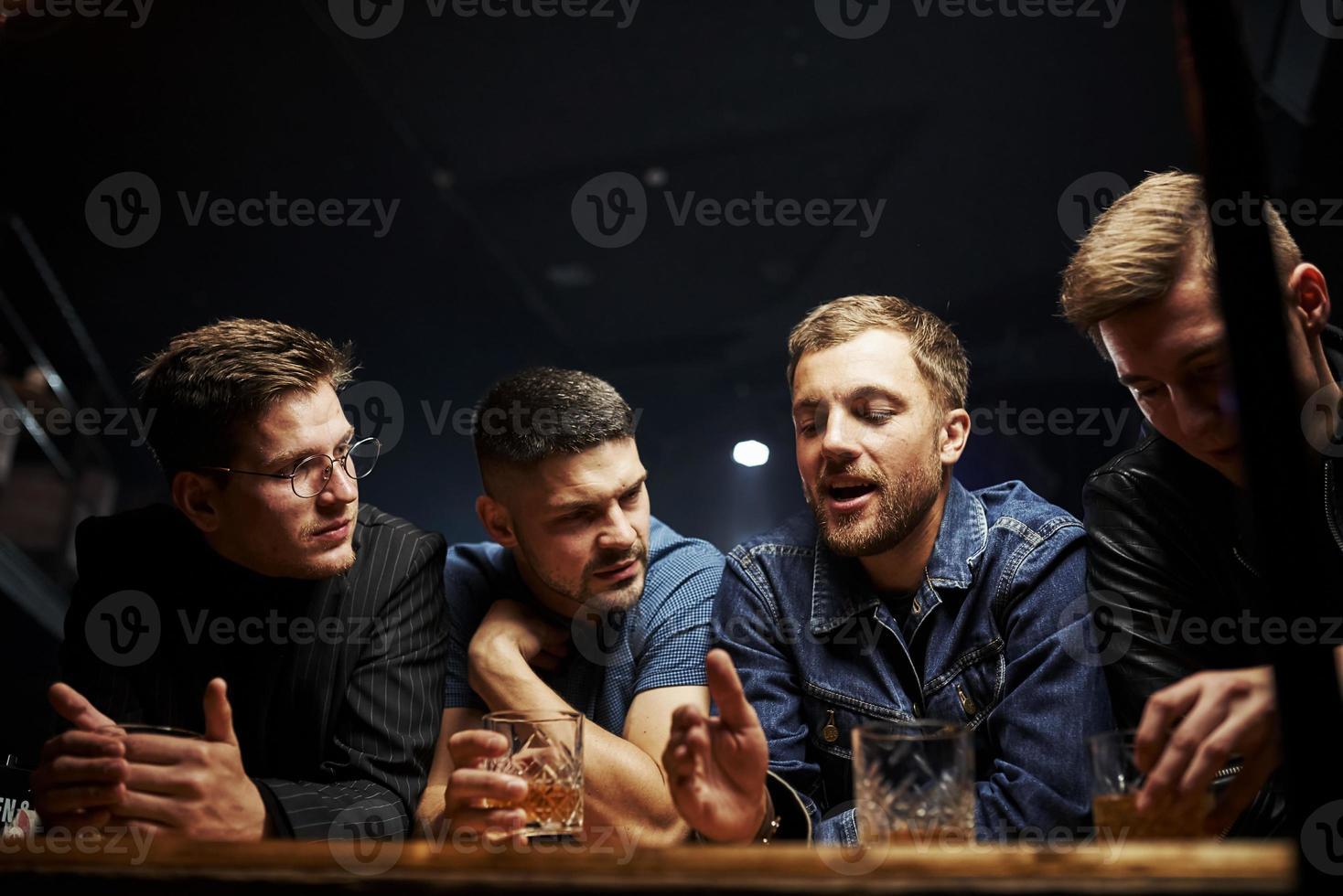 främre se. vänner vilar i de pub med alkohol i händer. har konversation foto