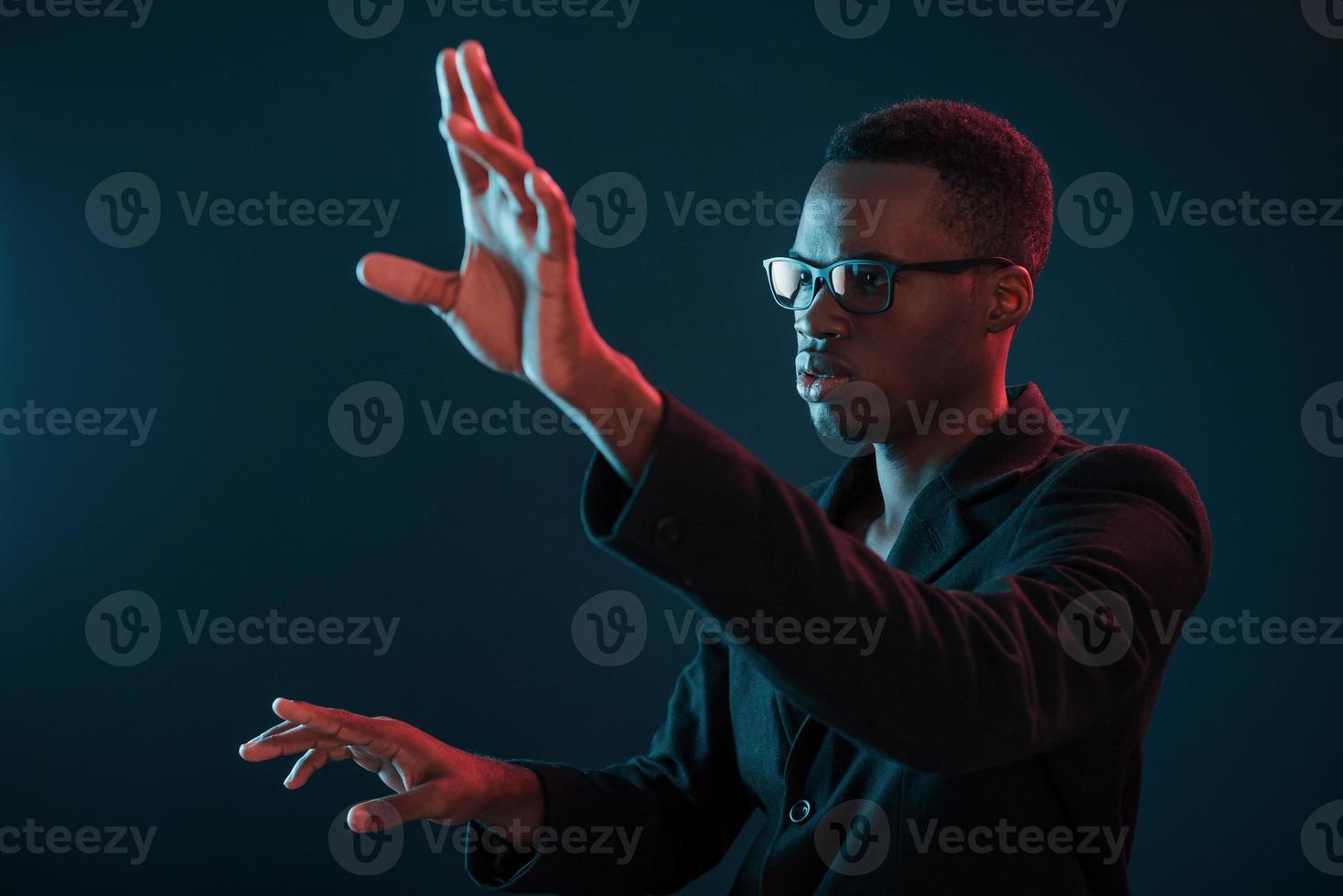 händer i främre. trogen neon belysning. ung afrikansk amerikan man i de studio foto