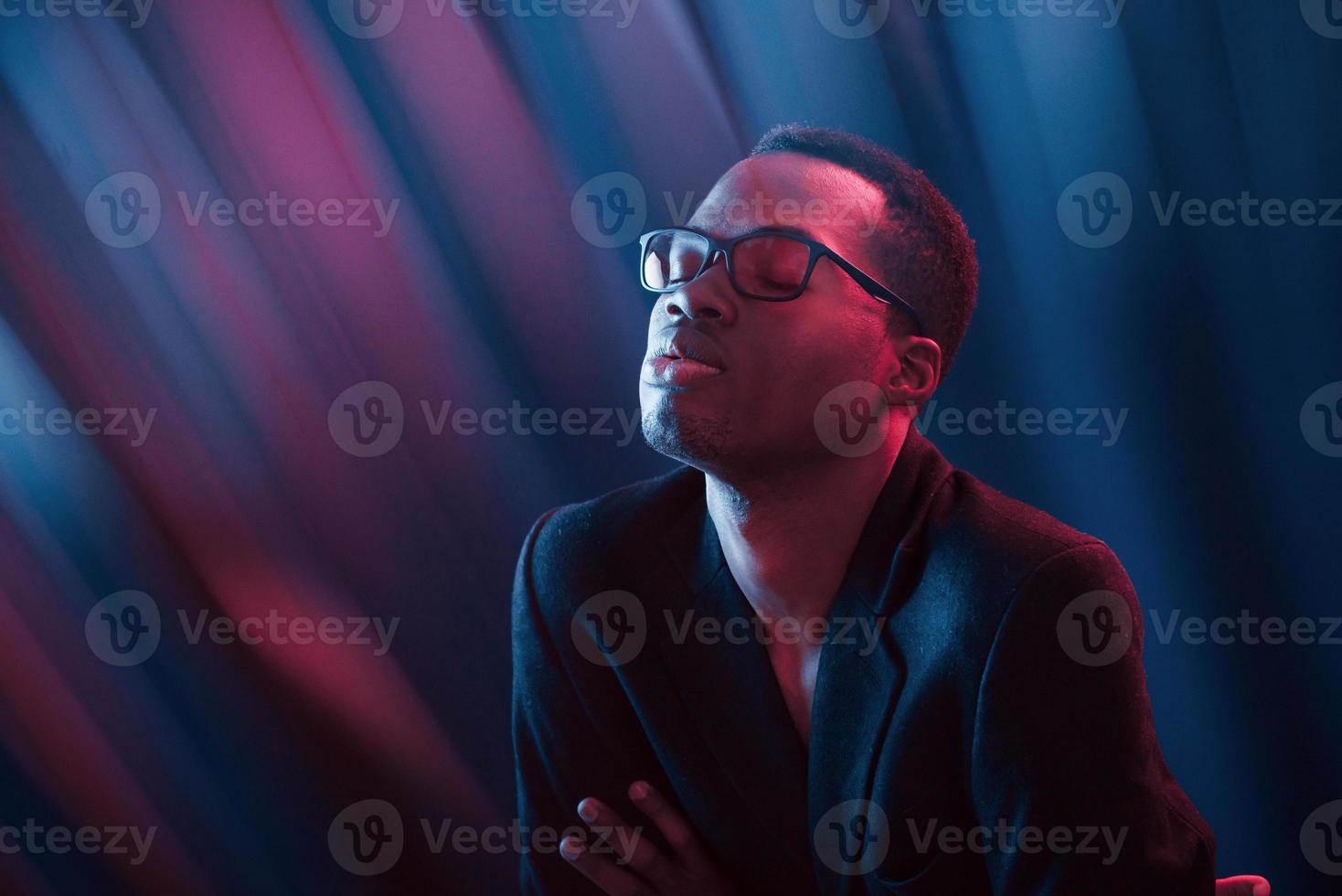 intressant strålar. trogen neon belysning. ung afrikansk amerikan man i de studio foto