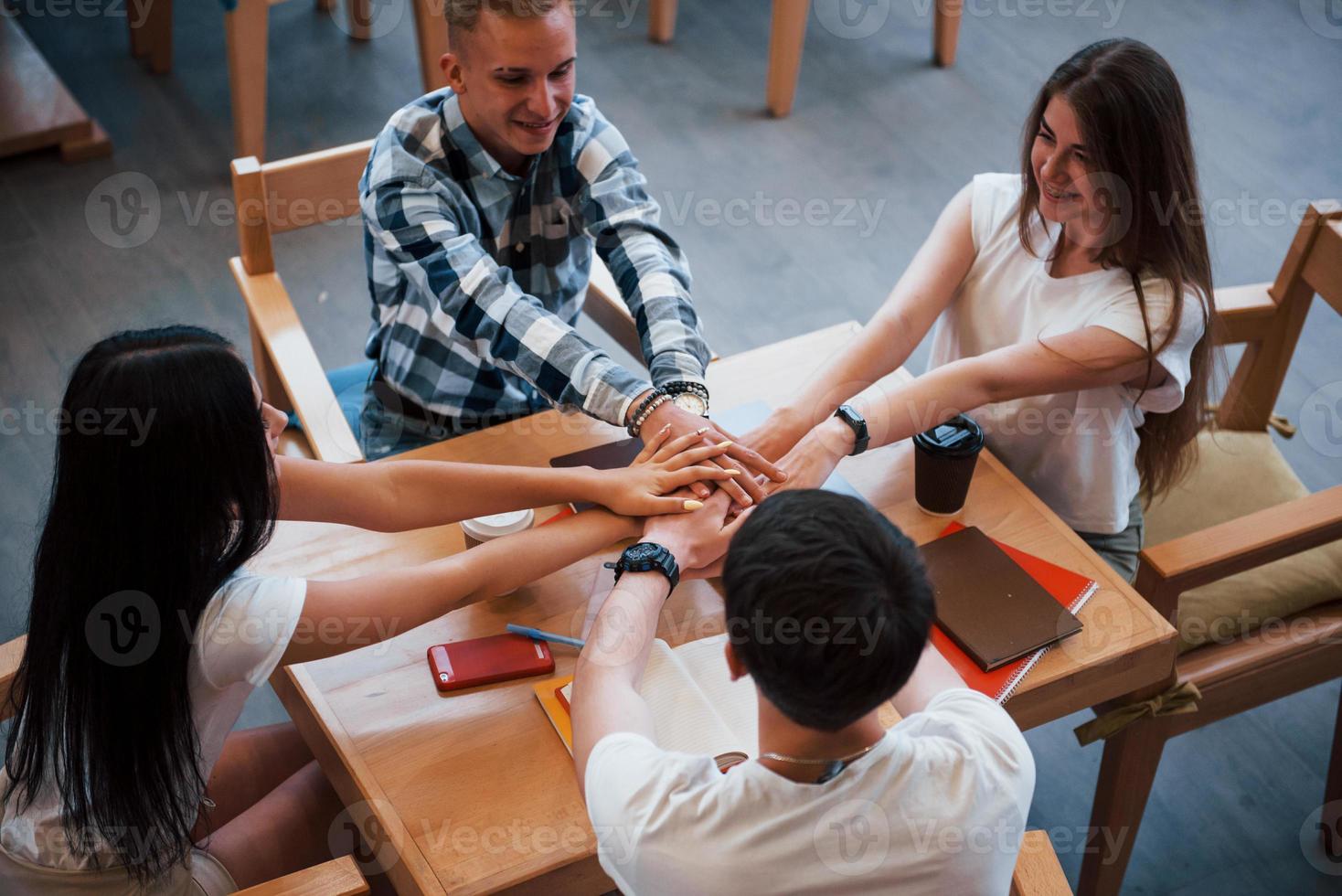 Sammanträde i Kafé och har konversation. fyra ung studenter i tillfällig kläder ha möte på regnig dag foto