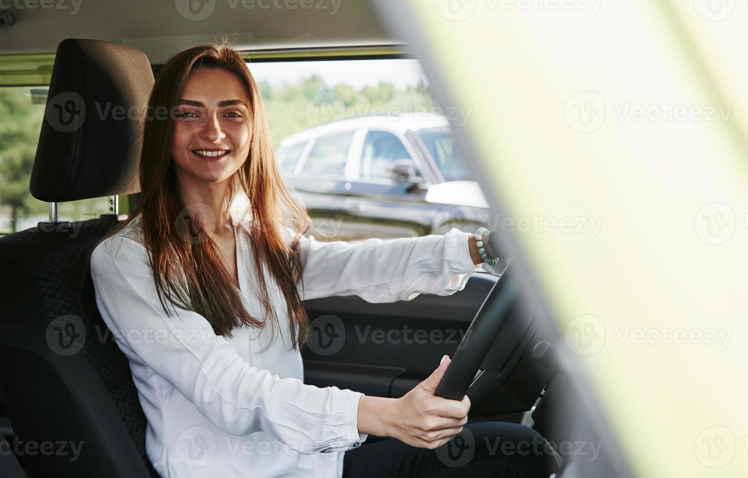 glad kvinna förare är i henne ny bil. interiör av modern bil foto