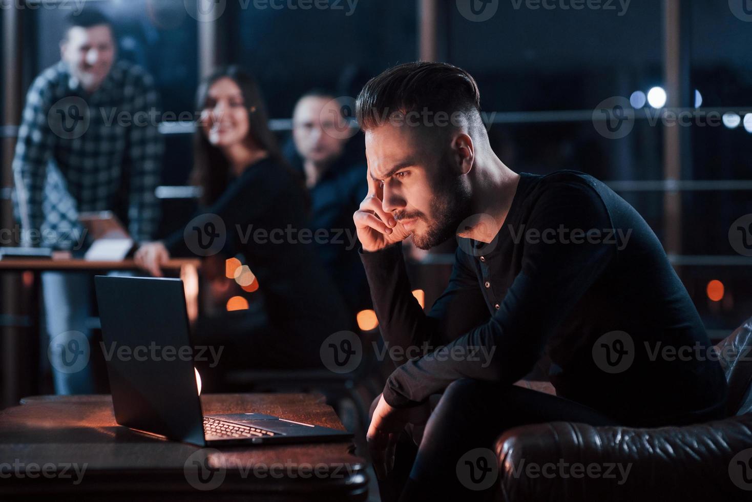 vänner på bakgrund är leende. team av ung företag människor Arbetar på deras projekt på natt tid i de kontor foto