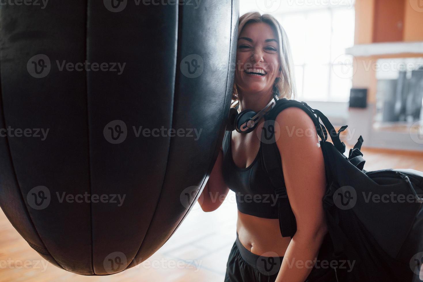 positiv person. vuxen kvinna med svart väska och hörlurar i de Träning Gym foto