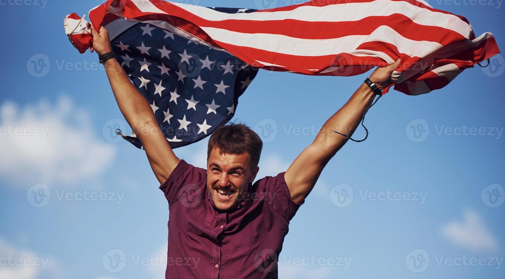 patriotisk Lycklig man vinka amerikan flagga mot molnig blå himmel foto