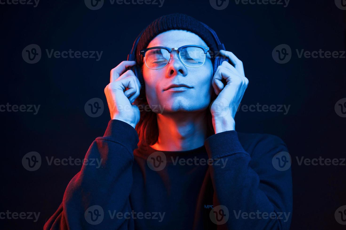 känna de musik. studio skott i mörk studio med neon ljus. porträtt av allvarlig man foto