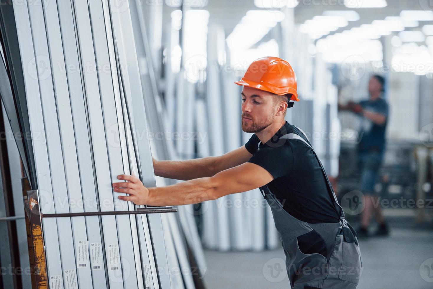 i de lagring med många av objekt. industriell arbetstagare inomhus i fabrik. ung tekniker med orange hård hatt foto