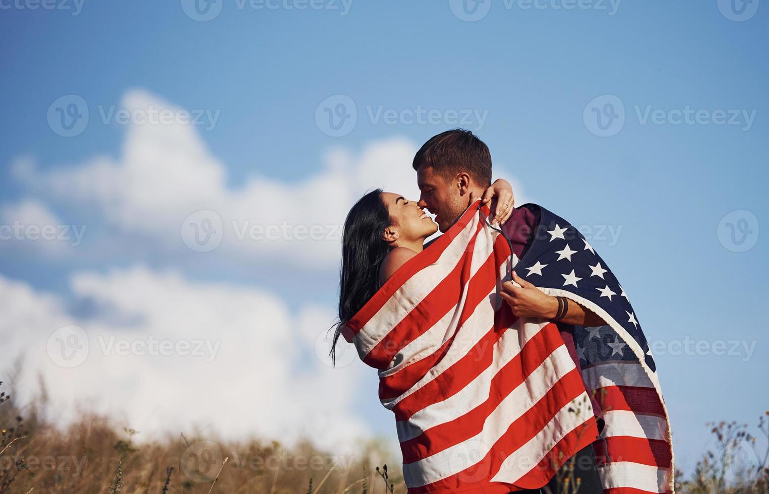 kissing varje Övrig. känner frihet. skön par med amerikan flagga ha en Bra tid utomhus i de fält foto