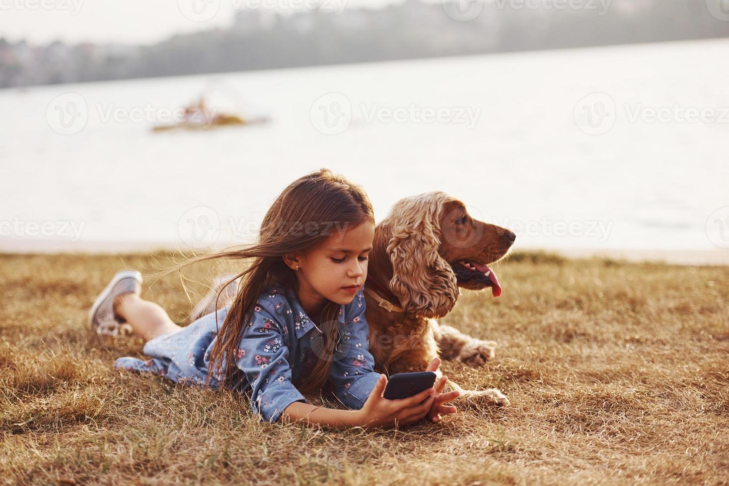 simning trasport behing på de sjö. söt liten flicka ha en promenad med henne hund utomhus på solig dag foto