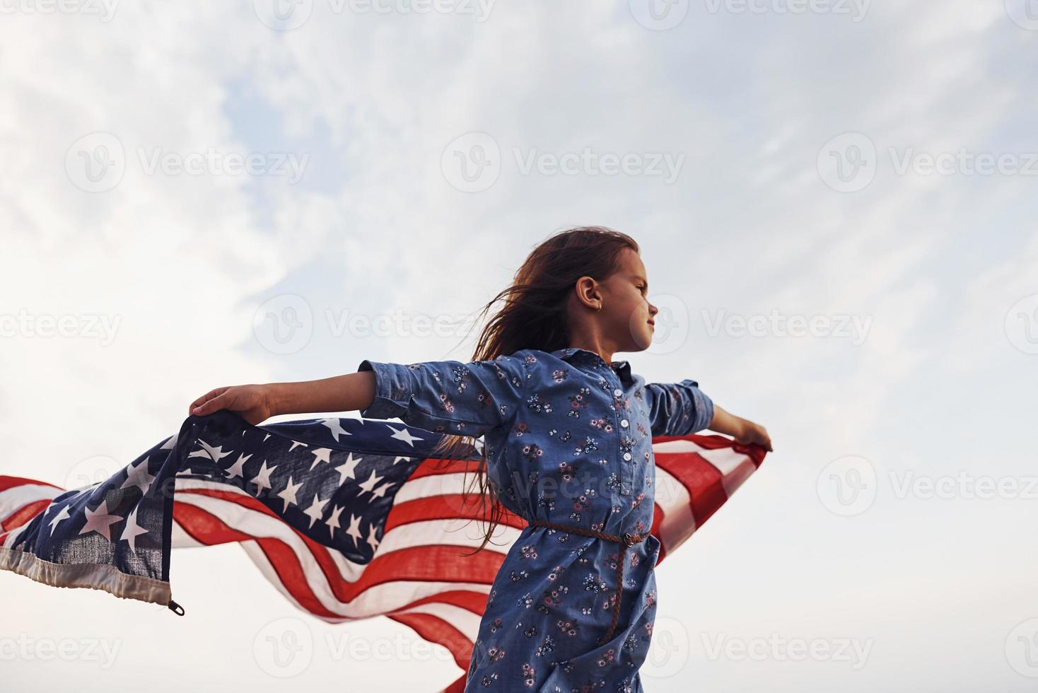 patriotisk kvinna unge med amerikan flagga i händer. mot molnig himmel foto